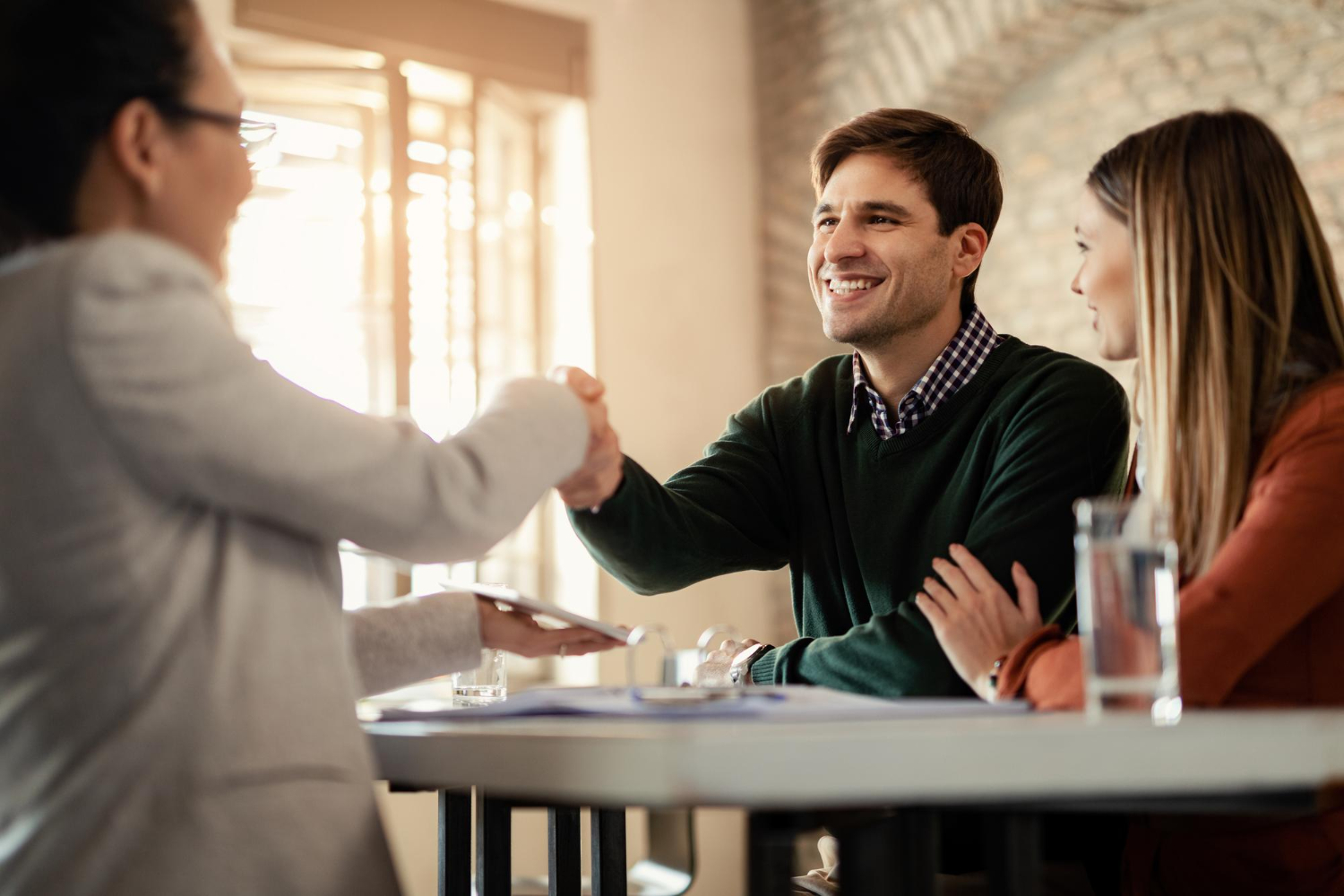 happy-couple-shaking-hands-with-financial-advisor-during-meeting-office-focus-is-man-1