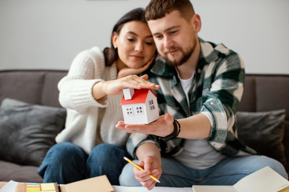 couple-holding-small-house-medium-shot